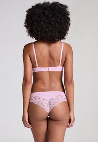 Set di lingerie rosa chiaro composto da un reggiseno in satin con spalline regolabili e un perizoma con schiena in pizzo e motivi floreali intricati.