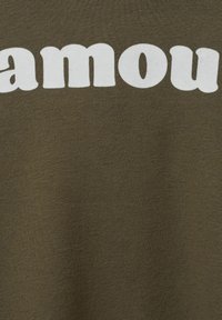 Olíva zöld pamut póló boldog fehér "famous" felirattal; puha textúra és normál szabás. Háttér és részletek nem included.