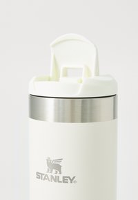 Bijeli nehrđajući čelik vakuumski izolirani tumbler s sjajnim srebrnim pojasom, opremljen svijetlom plastičnom kapicom i središnjim logotipom.