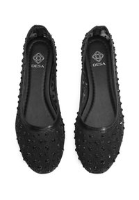 Schwarze Ballerinas mit einer strukturierten Oberseite, die mit erhöhten Nieten versehen ist. Glatte Sohlen mit einem schlichten Design und Logo auf der Innensohle.