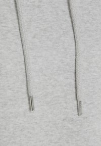 Ljusgrå hoodie-tyg med en slät textur, som har två dragsnören med metallögla på framsidan i mitten.