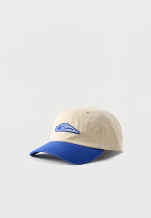 Beige honkbalpet met een blauwe gebogen klep en een blauw geborduurd golflogo op het voorpaneel, weergegeven op een witte achtergrond.