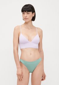 Világoslila bralette állítható pántokkal és mély V nyakkivágással, menta zöld, magas derekú bikini alsókkal párosítva. Sima anyag, minimális varrásokkal.