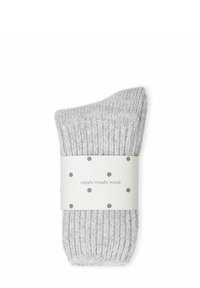 Calzino grigio chiaro lavorato a maglia con texture a coste, ripiegato al polsino, fissato con un nastro etichettato con pois e nome del marchio.