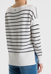 Gestreifter Pullover in Weiß und Marineblau, mit lockerer Passform, gerippten Bündchen und einem etwas längeren rückseitigen Saum. Weicher Strickstoff mit horizontalen Streifen.