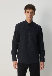 Marineblaues Hemd mit Knöpfen, das ein dezentes Muster aufweist, lange Ärmel, einen spitzen Kragen und eine Brusttasche hat. Hergestellt aus einem glatten Stoff.