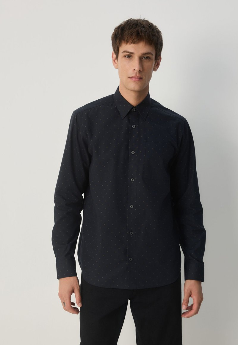 Marineblaues Hemd mit Knöpfen, das ein dezentes Muster aufweist, lange Ärmel, einen spitzen Kragen und eine Brusttasche hat. Hergestellt aus einem glatten Stoff.