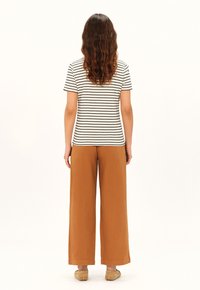 Top de manga corta a rayas en blanco y negro, combinado con pantalones sueltos de pierna ancha en marrón. Tela suave, corte relajado, sin patrones ni acentos visibles.