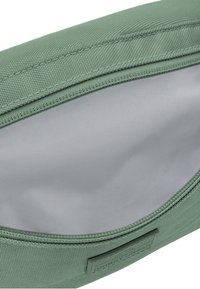 Borsa in tessuto verde con un esterno testurizzato, chiusura con zip e rivestimento interno grigio liscio. Presenta un logo in rilievo su un lato.