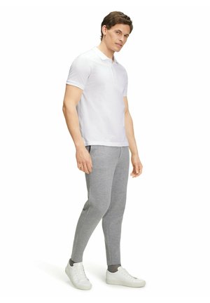 Biała koszulka polo z krótkim rękawem, w zestawie z szarymi dżinsami slim-fit i białymi sneakersami. Gładka tekstura, prosty design.
