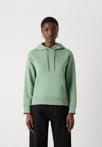 Grön hoodie i mjukt material, med en känguruficka, justerbar dragsko på huvan och ribbade ärmslut och fåll.