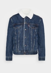 Mörkblå denimjacka med krage av vit fuskfårskinn, knäppning med knappar, två bröstfickor och sidofickor, med en lätt sliten finish.
