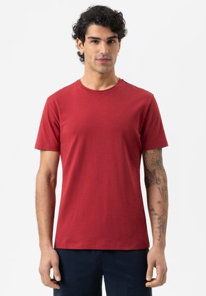 Rotes Baumwoll-T-Shirt mit Rundhals-Ausschnitt und kurzen Ärmeln, mit glatter Textur und schlichtem Design, getragen von einem Model.