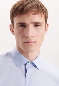 Lichtblauw overhemd met knoopsluiting en een klassieke kraag, gemaakt van een gladde stof en voorzien van subtiele stikseldetails in een getailleerd ontwerp.