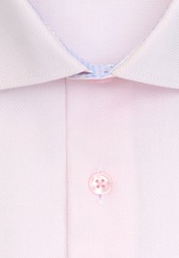 Chemise rose clair en tissu texturé, dotée d'une fermeture à boutons avec un bouton rose à quatre trous, et d'un col classique avec des accents de surpiqûres bleues.
