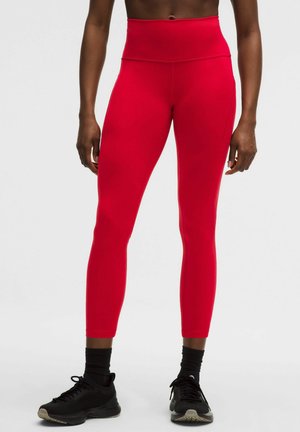 Červené legíny s vysokým pásom vyrobené z elastickej tkaniny. Priliehavý strih s hladkou textúrou, dĺžka po členky a švy do plochy pre väčšie pohodlie.