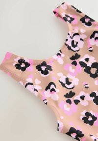 Puha bézs alapszínű fürdőruha, rózsaszín, fekete és fehér virágmintával díszítve. Kerek nyakkivágással és varrott szélekkel rendelkezik.