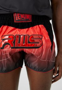 Rote und schwarze VENUM-Shorts mit glänzendem "RULS"-Grafikdesign, strukturiertem Stoff, elastischem Bund und kontrastierenden Nähdetails.