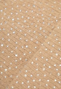 Tkanina světle hnědé barvy s rozptýlenými stříbrnými krystaly, s měkkým, plyšovým povrchem a diagonálním vzorem vystouplých teček.
