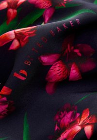 Satin audums ar tumšu fonu un dzīvīgu rozā un sarkano ziedu rakstu. Zīmola nosaukums "b'Y TED BAKER" ir smalki iekļauts.