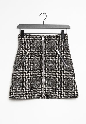 Falda de cuadros en blanco y negro con una tela texturizada, que incluye un zipper centrado y dos bolsillos laterales con herrajes plateados.