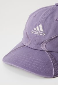 Purple Adidas baseball cap with white embroidered logo and curved brim on white background.