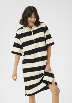 Robe polo à rayures noires et crème avec des manches courtes, un rabat zippé, des fentes sur les côtés et une coupe décontractée. Tissu doux avec une texture lisse.