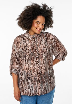 Chemise à imprimé animal dans des tons bruns et beiges, avec un design à boutons, des manches longues, deux poches poitrine et une coupe décontractée.