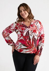 Blusa floreale con scollatura a V, caratterizzata da motivi di foglie rosa e rosse su sfondo bianco, maniche lunghe con polsini arricciati; materiale leggero.
