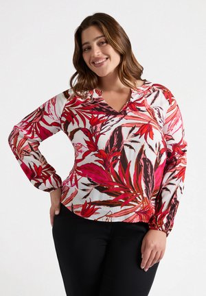Bloes met bloemenprint en v-hals, met roze en rode bladdessins op een witte achtergrond, lange mouwen met gatherings aan de manchetten; lichte stof.