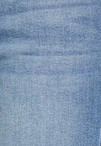 Tecido de denim azul claro com uma textura subtil, apresentando linhas discretas e um acabamento suave, adequado para vestuário casual como calças de ganga.