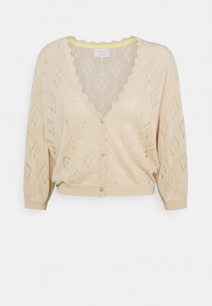 Beige gestrickte Strickjacke mit einem strukturierten Rautenmuster, gewelltem Ausschnitt und drei blauen Knöpfen auf der Vorderseite. Kurze, puffige Ärmel.