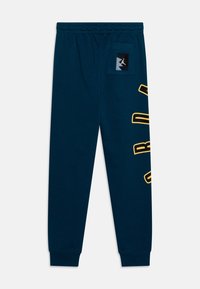 Marineblaue Jogginghose mit elastischem Bund, einer Seitentasche und gelbem "JORDAN"-Schriftzug am linken Bein. Weiches Baumwollmischmaterial.