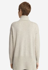 Hellbeige Rollkragenpullover mit gerippten Akzenten am Saum und an den Bündchen, aus weichem, strukturiertem Material. Lange Ärmel, oversize Schnitt.
