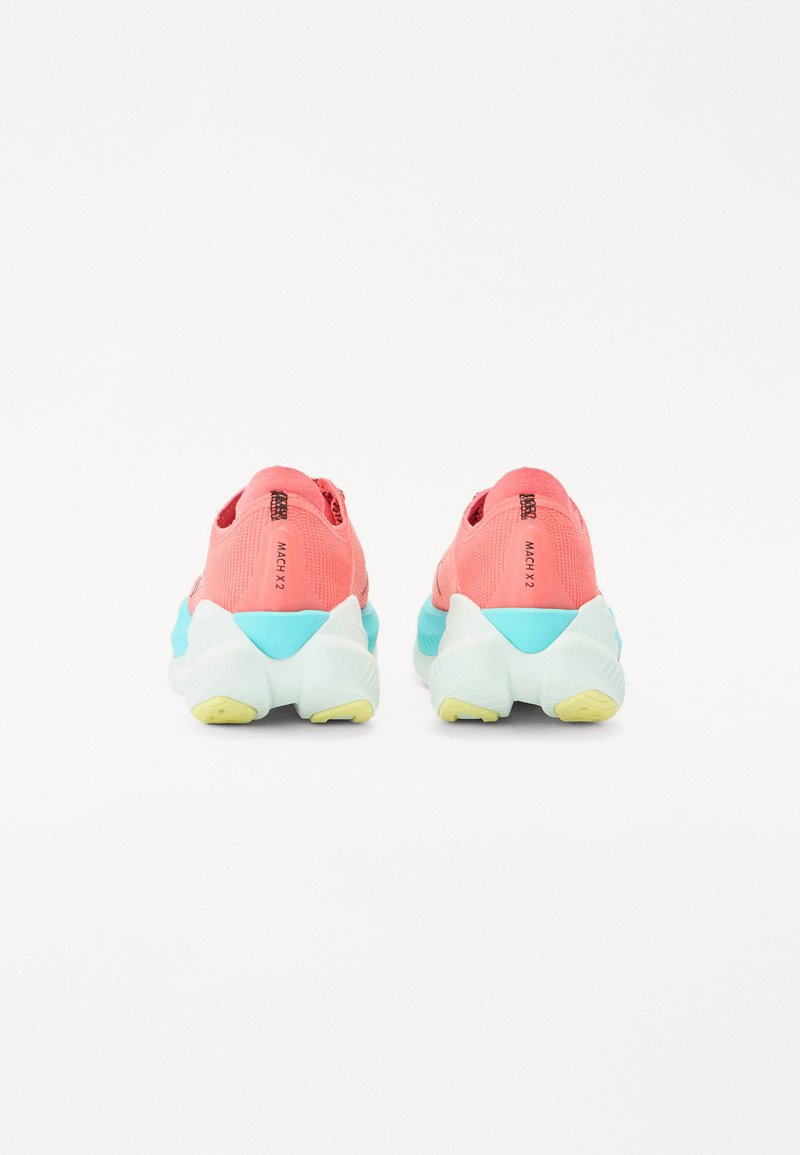 Chaussures avec une tige en tricot rose dotée de détails en mesh, des accents turquoise sur la semelle et un détail de semelle extérieure jaune. Design étiqueté "MACH X 2."