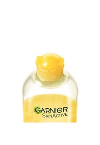 Clear plastflaska med ett gult lock, innehållande en gul vätska. Har en "Garnier SkinActive" etikett i svart text med gröna detaljer.