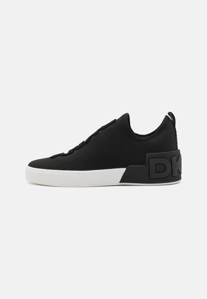 Black athletic sneakers with a textured fabric upper, featuring a white rubber sole and a prominent black logo accent on the heel.