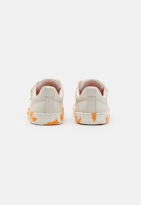 Sneakers bianchi in pelle con una finitura testurizzata, caratterizzati da un motivo astratto arancione e bianco sulla suola in gomma e un collare imbottito.