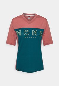 Camiseta de manga corta, con cuello en V, en rosa y verde azulado, con "MONS ROYALE" en letras amarillas en negrita a lo largo del pecho. Tejido suave, ajuste casual.
