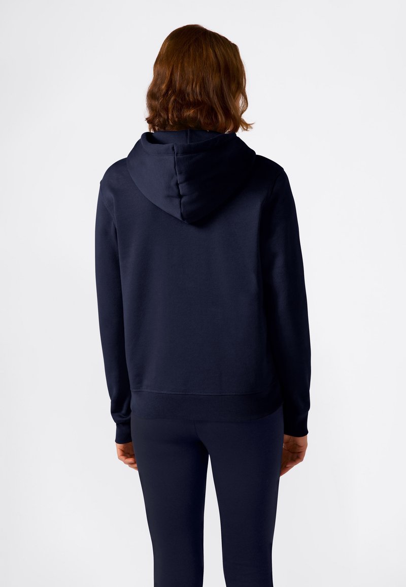 Sudadera con capucha de color azul marino, con puños y dobladillo acanalados, hecha de una tela suave, vista desde la parte de atrás, combinada con leggings a juego.