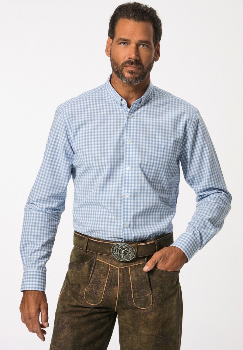 Camisa a cuadros en azul y blanco con cuello abotonado, combinada con lederhosen marrones que presentan costuras decorativas y una hebilla de cinturón metálica.