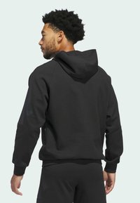 Schwarzer Kapuzenpullover aus strukturiertem Stoff, mit gerippten Bündchen und einem Design des Rückenteils. Schlichte und funktionale Passform mit minimalen Details.