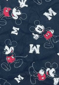 Marineblauer Stoff mit einem sich wiederholenden Muster von Cartoon-Mickey-Maus in roten Shorts, schwarzen Schuhen und weißen Handschuhen, neben weißen Buchstaben 'M' Akzenten.