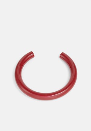 Brazalete rojo brillante con una forma suave y redondeada. El diseño es minimalista, con un color sólido y sin adornos adicionales.