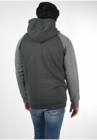 Sudadera con capucha de cuerpo gris oscuro y mangas raglán gris claro. Tejido de mezcla de algodón con un ajuste relajado y puños y dobladillo de canalé.