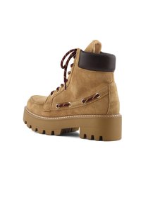 Botín de ante marrón con un cuello de cuero oscuro en contraste, suela de goma gruesa y cordones burdeos pasados por ojales dorados.