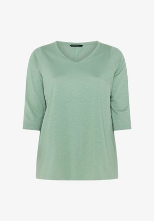 Lysegrøn damebluse med trekvartlange ærmer og V-udskæring, lavet af blødt, let tekstureret stof.