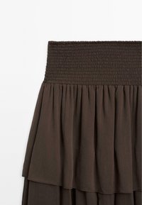 Gonna a strati marrone realizzata in tessuto leggero, con un elastico in vita e strati morbidi e fluenti per un tocco di texture aggiuntivo.