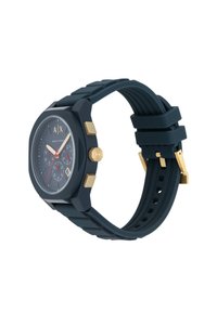 Orologio da polso in silicone nero con cassa angolare, accenti dorati, lancette rosse e cinturino testurizzato. Presenta una finestra per la data e tre sottodial.