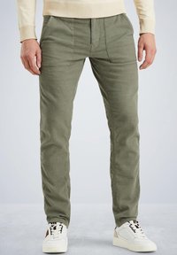 Pantalones de algodón verde olivo con corte recto, que cuentan con bolsillos frontales y una tela texturizada, combinados con zapatillas blancas.